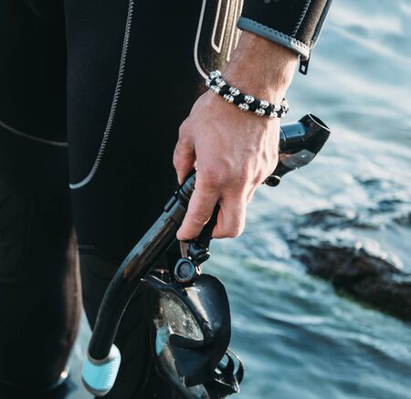 Close-up of diver male hand with snorkel mask on background of seaの写真素材