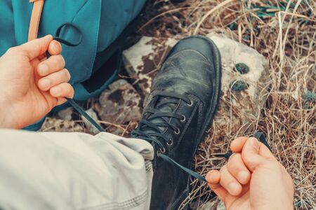 Hiker man tying shoelaces on nature outdoor, near backpack. Point of view shotの写真素材