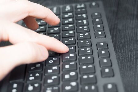 Pressing the keyboard closeup. Black keyboard on the desk