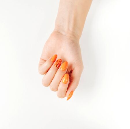 Womanâs hand with autumn stylish orange color manicure on a white background.の写真素材