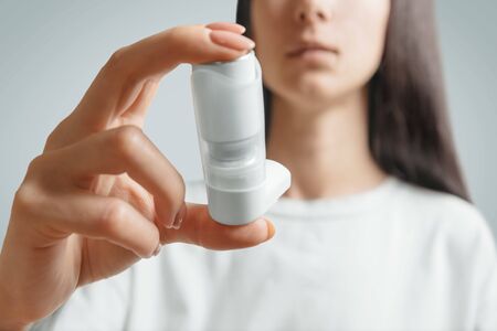 Brunette young woman holding inhaler against asthma attack, medical treatment.の写真素材