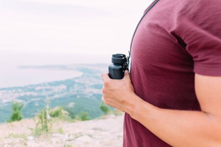 Unrecognizable man standing with binoculars in nature outdoor.