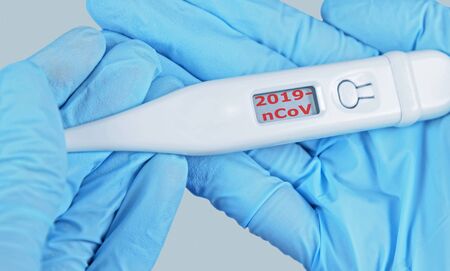 Medical hands in protective gloves holding electronic thermometer 2019-nCov on display. Coronavirus...
