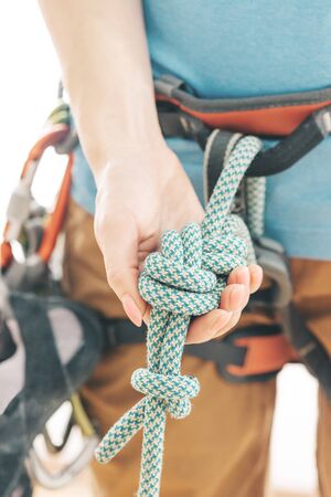 Unrecognizable sporty woman climber in safety harness holding rope knot eight, close-up.の写真素材