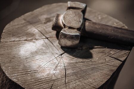 Metal hammer on a wooden stump in the workshop of a blacksmith.