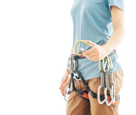 Unrecognizable woman climber in safety harness holding snap hook carabiner on a white background...