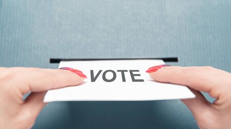 Unrecognizable woman putting a ballot list into a voting box, point of view in first person. Elections.の写真素材