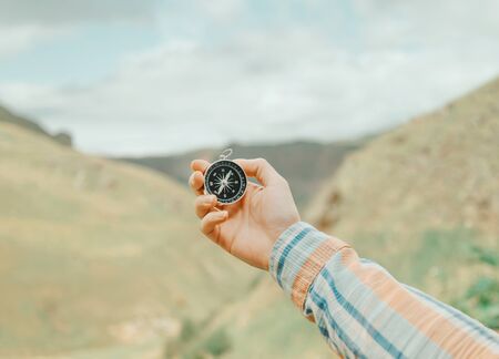 Hiker young woman holding magnetic compass in a hand and searching direction in summer mountains valley, point of view.の写真素材