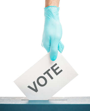Male hand in protective glove putting a vote ballot into a box on a white background. Elections.の写真素材