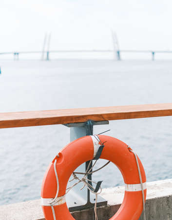 Red lifebuoy hanging on fence near sea.の写真素材