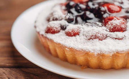 Simple homemade pie with strawberries and cherries on a wooden table.の写真素材