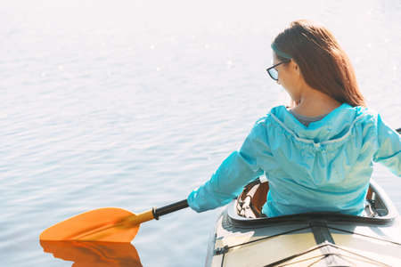 Water tourism. The female traveler looks at the paddle while paddling.