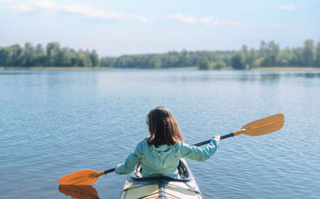 The woman is enjoying kayaking. Purity and silence of Nature. Calm water.
