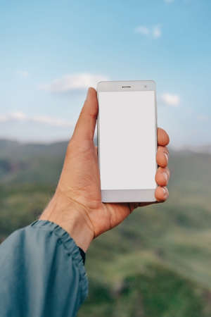 Smartphone with blank screen in a male hand outdoor.