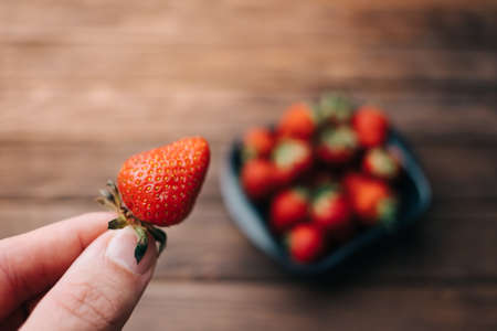 Man shows a close-up of ripe strawberries.の写真素材