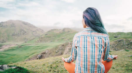 Woman traveler meditates in the lotus position. Rear view.