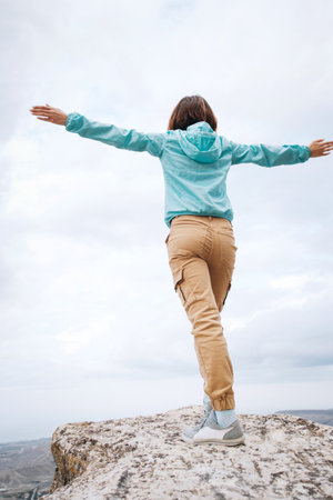 Young woman stands on the top of a mountain.
