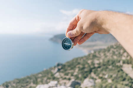 Compass in male hands in the background sea and mountains.の写真素材