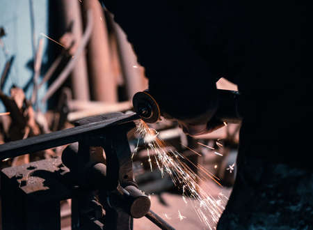 Blacksmith cuts a metal plate with a circular saw.の写真素材