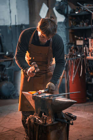 Blacksmith is working on an anvil, forging a red-hot metal blank.の写真素材