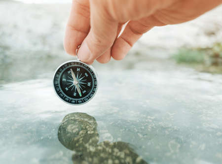 Man holds a compass above the water.の写真素材