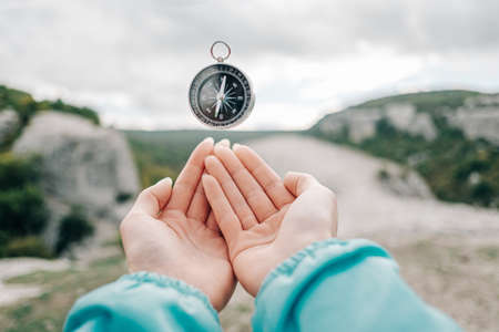 Compass hovers in levitation over female hands in the background nature.の写真素材