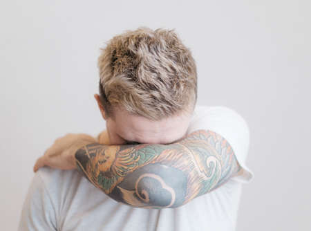 Portrait of a modern young guy with a tattoo on his arm.