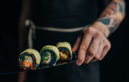 Man chef holds sushi rolls on a knife.の写真素材