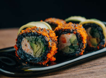 Bright Japanese sushi rolls with black rice, avocado and tobiko caviar.の写真素材