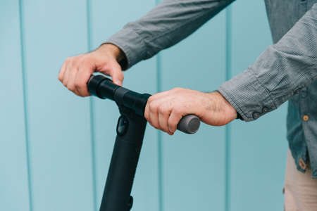 Close-up on the hands of a young man who are holding the steering wheel of an electric scooter.の写真素材