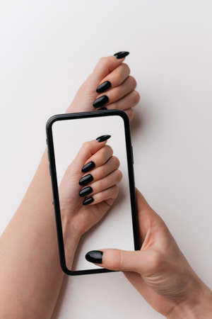 Close-up of a woman using her phone to take a photo of her manicure.の写真素材