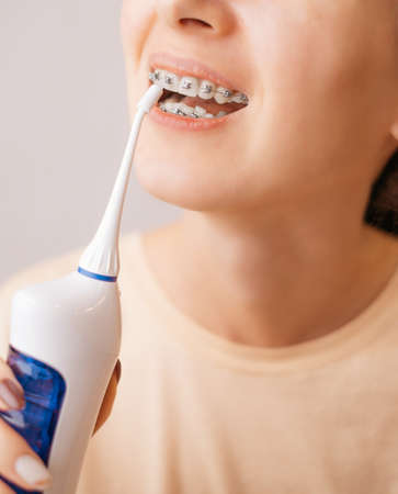 Woman washing a braces with an irrigator for dental health.の写真素材