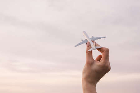 Airplane model in a female hand in the background sky.の写真素材