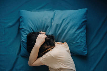 A woman lies in bed with a headache.の写真素材