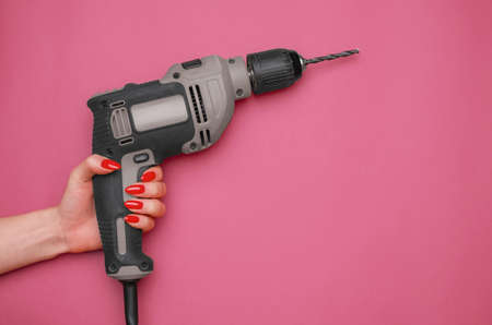 Female hand with a red manicure and an electric drill.の写真素材