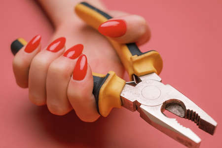 Close-up of a female hand with red manicure and pliers.の写真素材