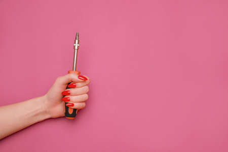 Female hand with a red manicure and a screwdriver.の写真素材