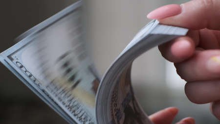 Close-up of female hands demonstrating a bundle of us dollars.の写真素材