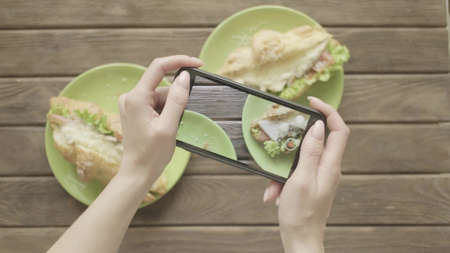 Woman food blogger takes a photo on her smartphone of her breakfast.
