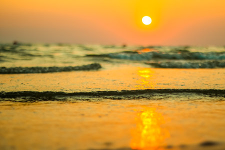 Wet sea sand on beach against background beautiful golden sunset. Close up sea sand on shore ocean...