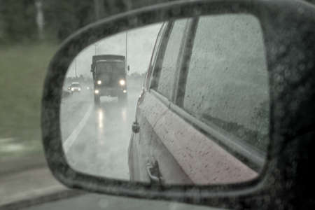 Side mirror of a car with raindrops. Safety on the road. Bad visibilityの写真素材