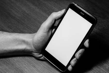 Empty, blank, white screen smartphone. Gadget in hand close up with free copy space for design or textのeditorial素材