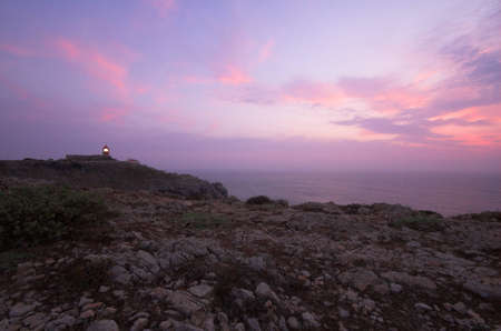 Mediterranean sunset near a lighthouse on the cliffsの写真素材