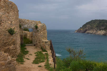 Stone building with gate with grating on the sea and clouds in the backgroundの写真素材
