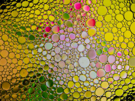 Oil bubbles of color pink, green and yellow on the water surfaceの写真素材