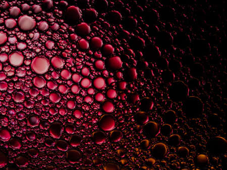 Oil bubbles of color red and black on the water surface