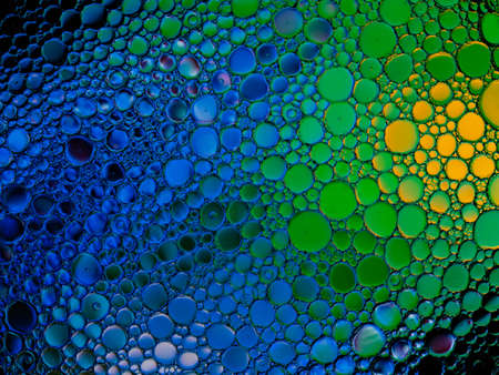 Oil bubbles of color blue, green and yellow on the water surface