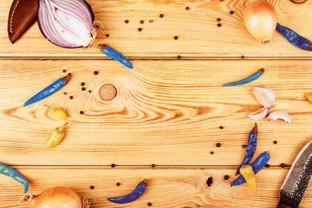Flatlay wooden background with vegetables, blue pepper, hunting knifeの写真素材
