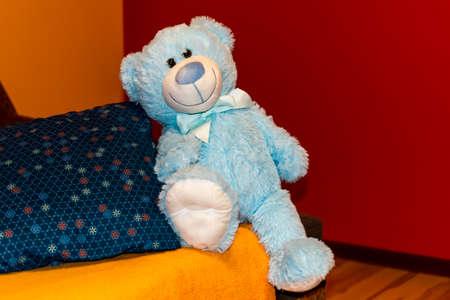 A blue teddy bear is sitting on a couchの写真素材
