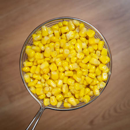 yellow canned corn has a colander in macroの写真素材
